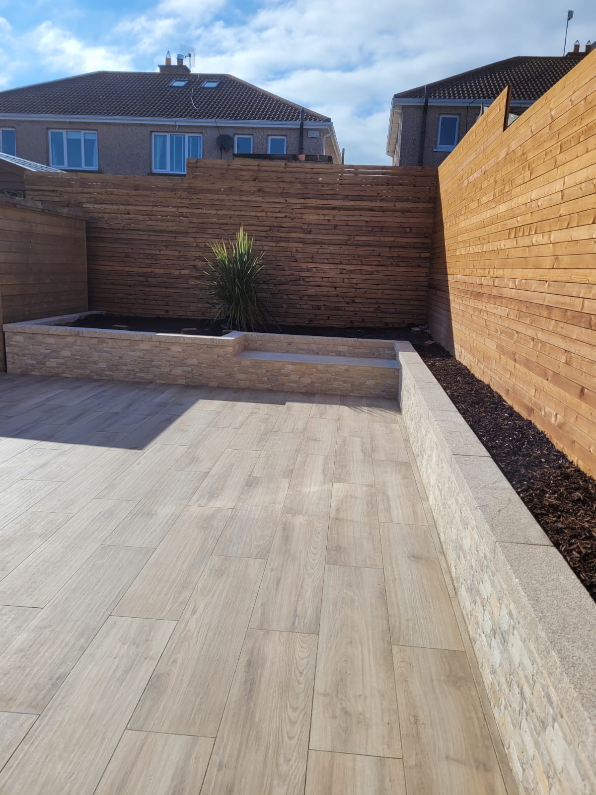 Wood effect patio with flower bed around the perimeter
